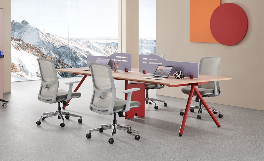 Un bureau pour quatre personnes avec rabats et quatre chaises de bureau en maille grise dans le bureau.