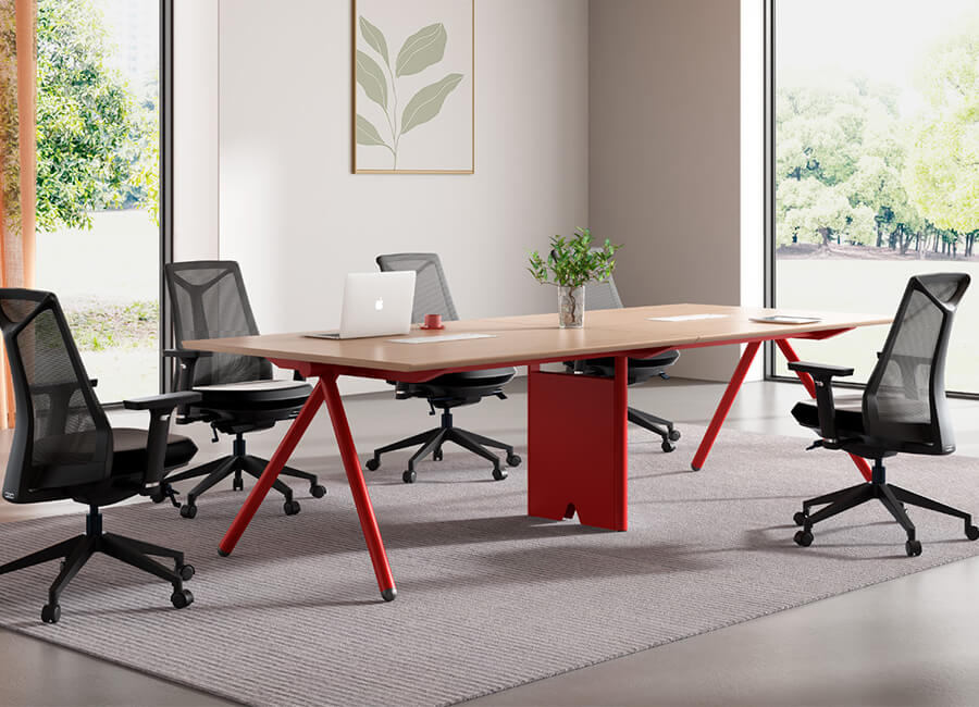 Une petite table de conférence avec un coin rouge et 4 chaises de bureau en résille noire à roulettes